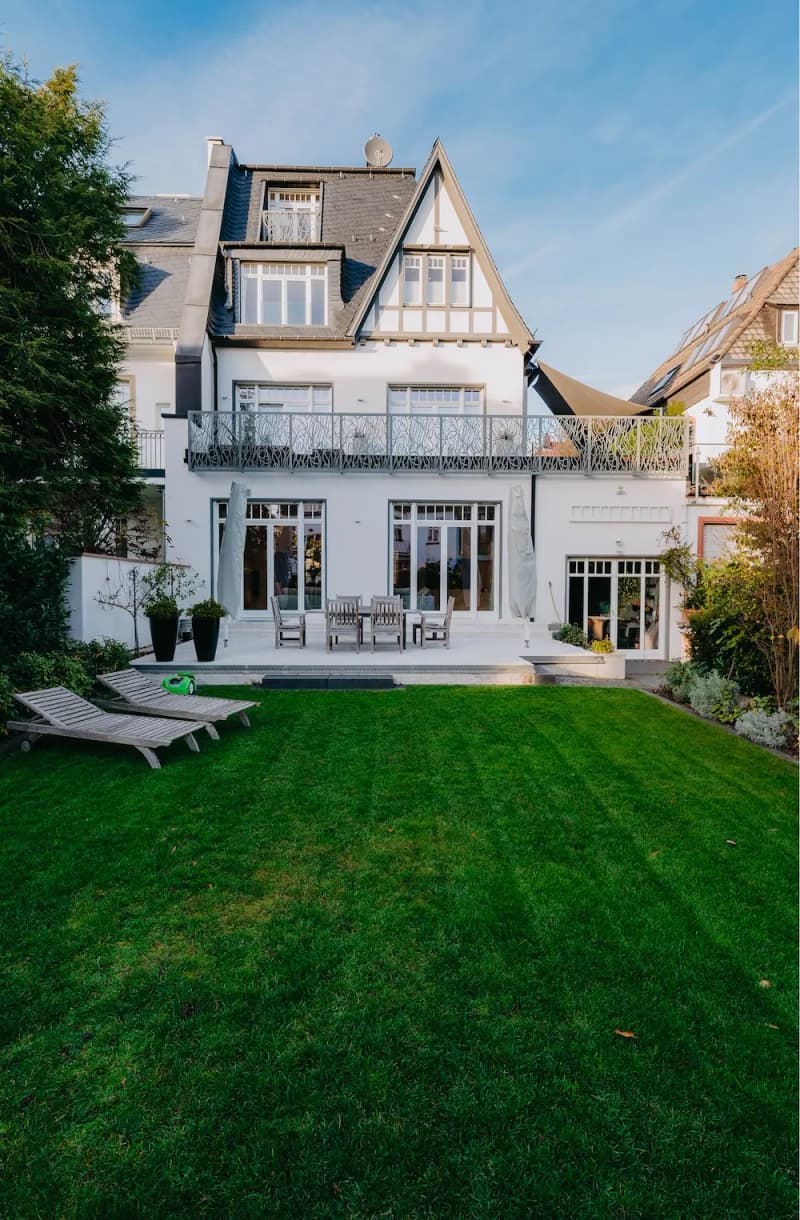 Large white house with garden, terrace and sun loungers on the lawn