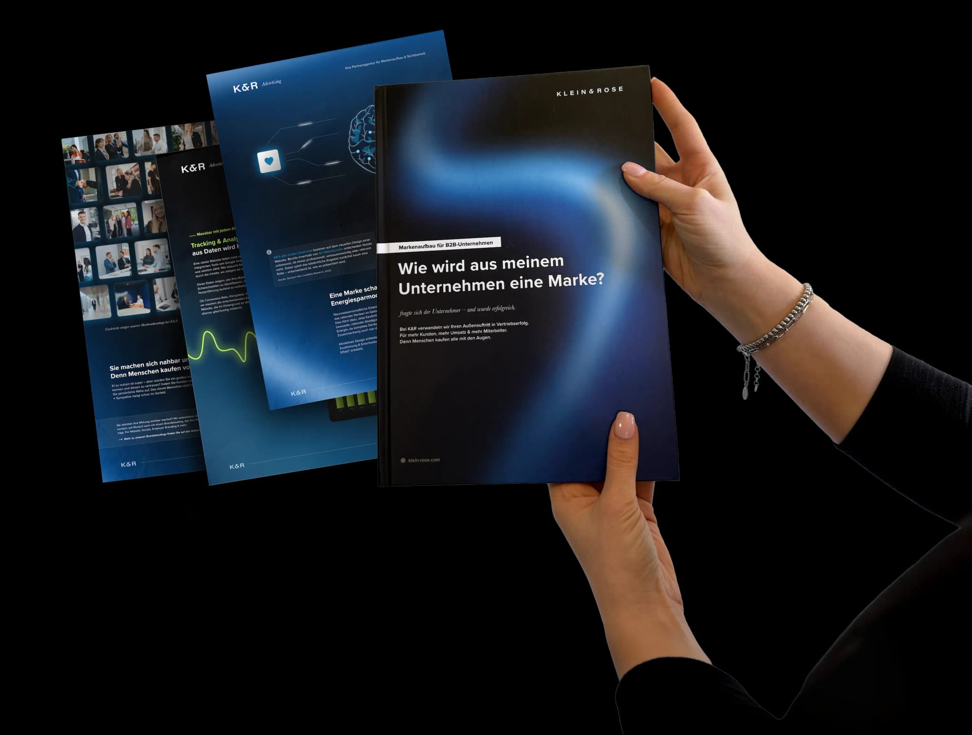 Hands holding the K&R brand handbook, tablets with website designs in the background