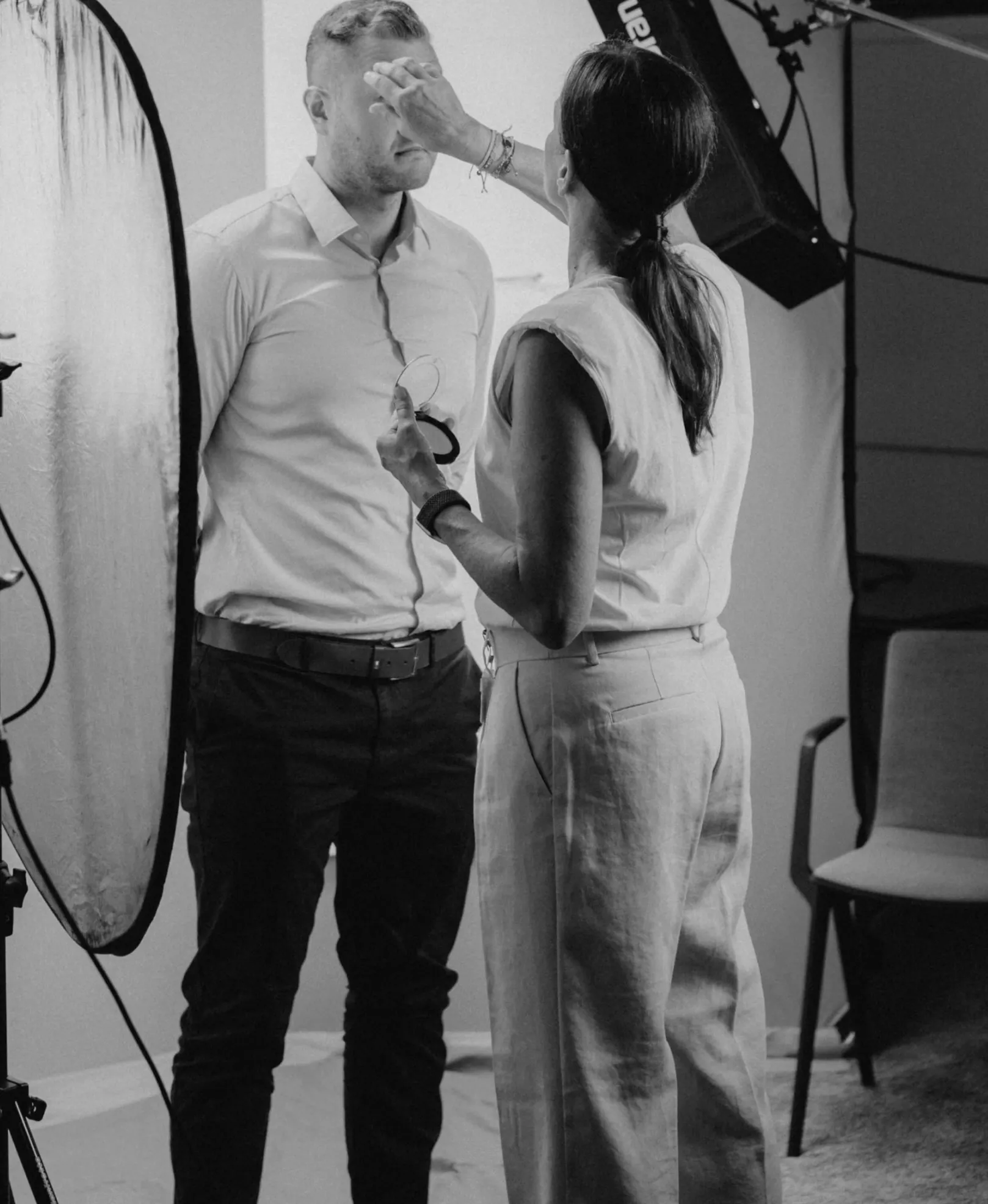 Woman applying make-up to a man in the photo studio