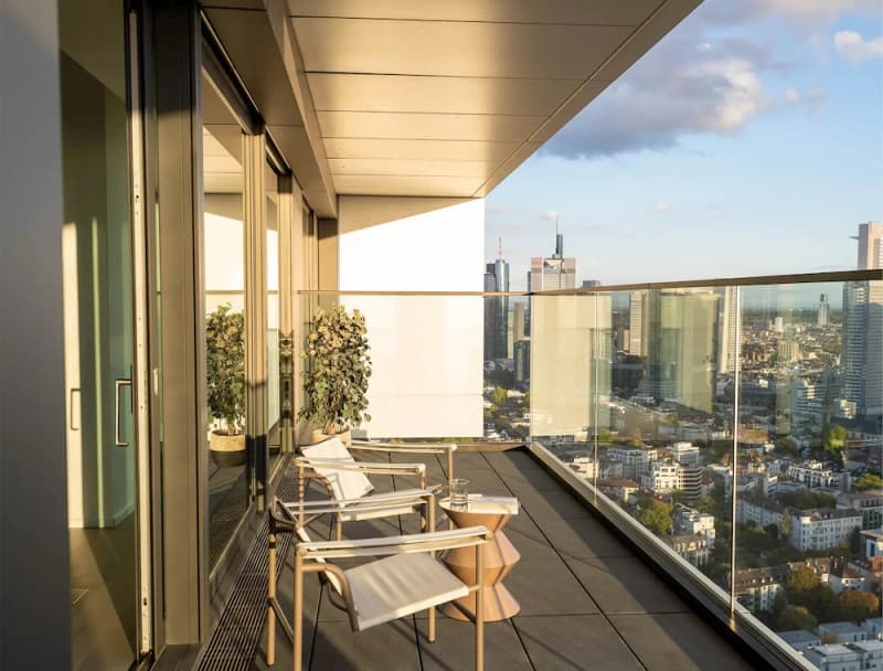 Modern balcony with chairs and a view of the city in sunlight