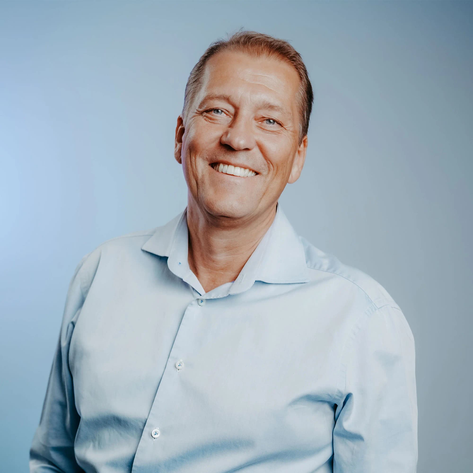 Smiling man in a light shirt against a blue background
