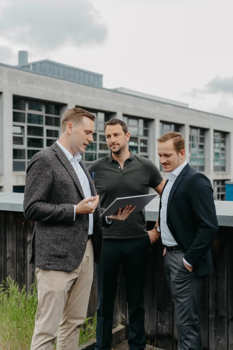 VAP team: three men with a tablet in front of a modern building in Frankfurt